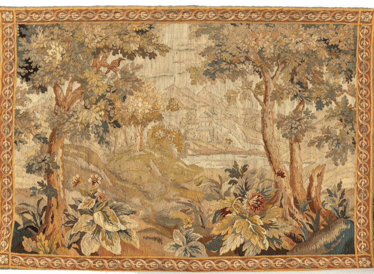 A reproduction of an 18th Century Flemish verdure tapestry featuring a serene landscape with stately trees, exotic birds, and blooming flora, enclosed in an ornate border.