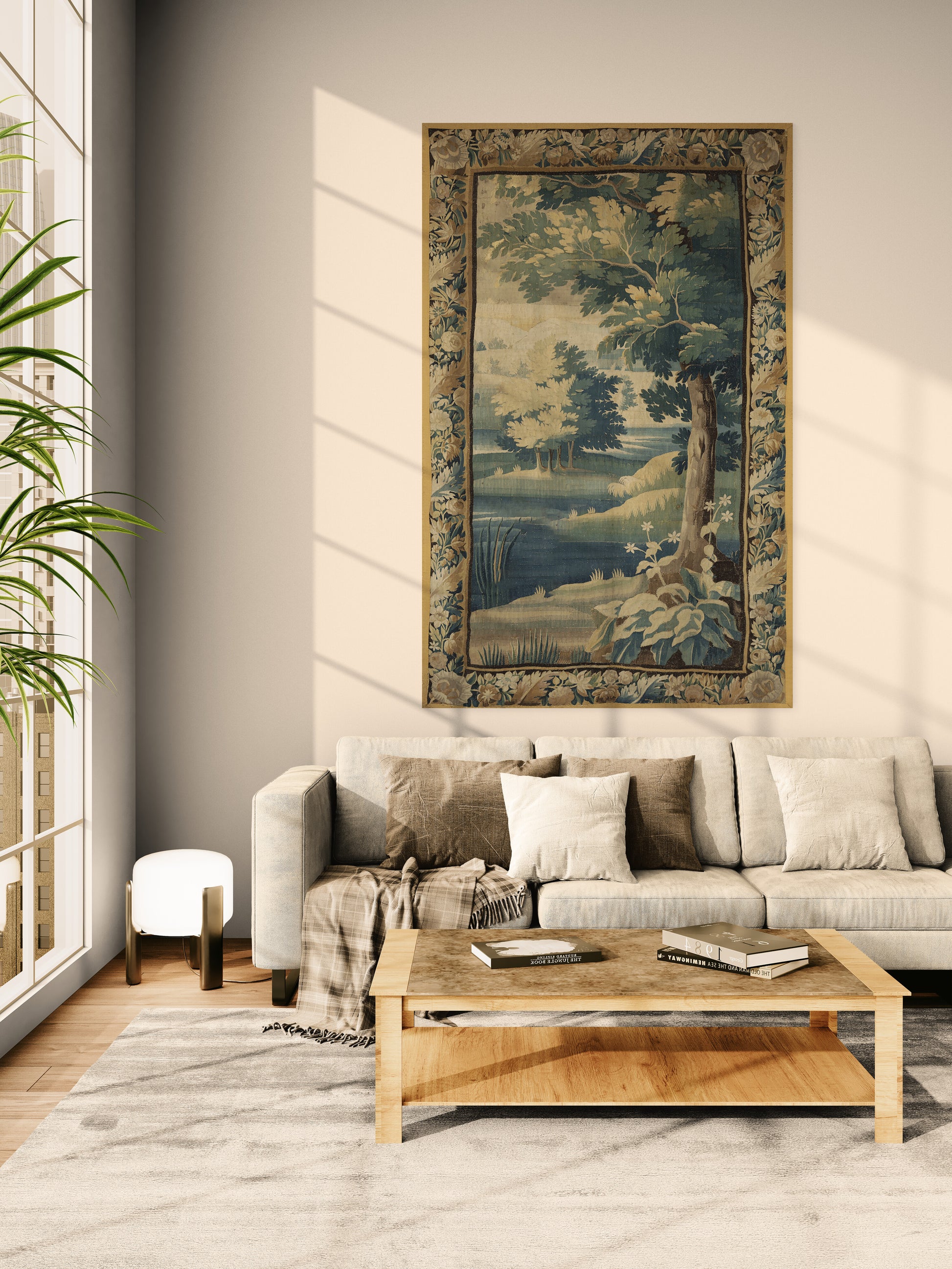 A large framed landscape tapestry with a detailed tree and river scene hangs on a beige wall above a light gray sofa in a modern living room setting.