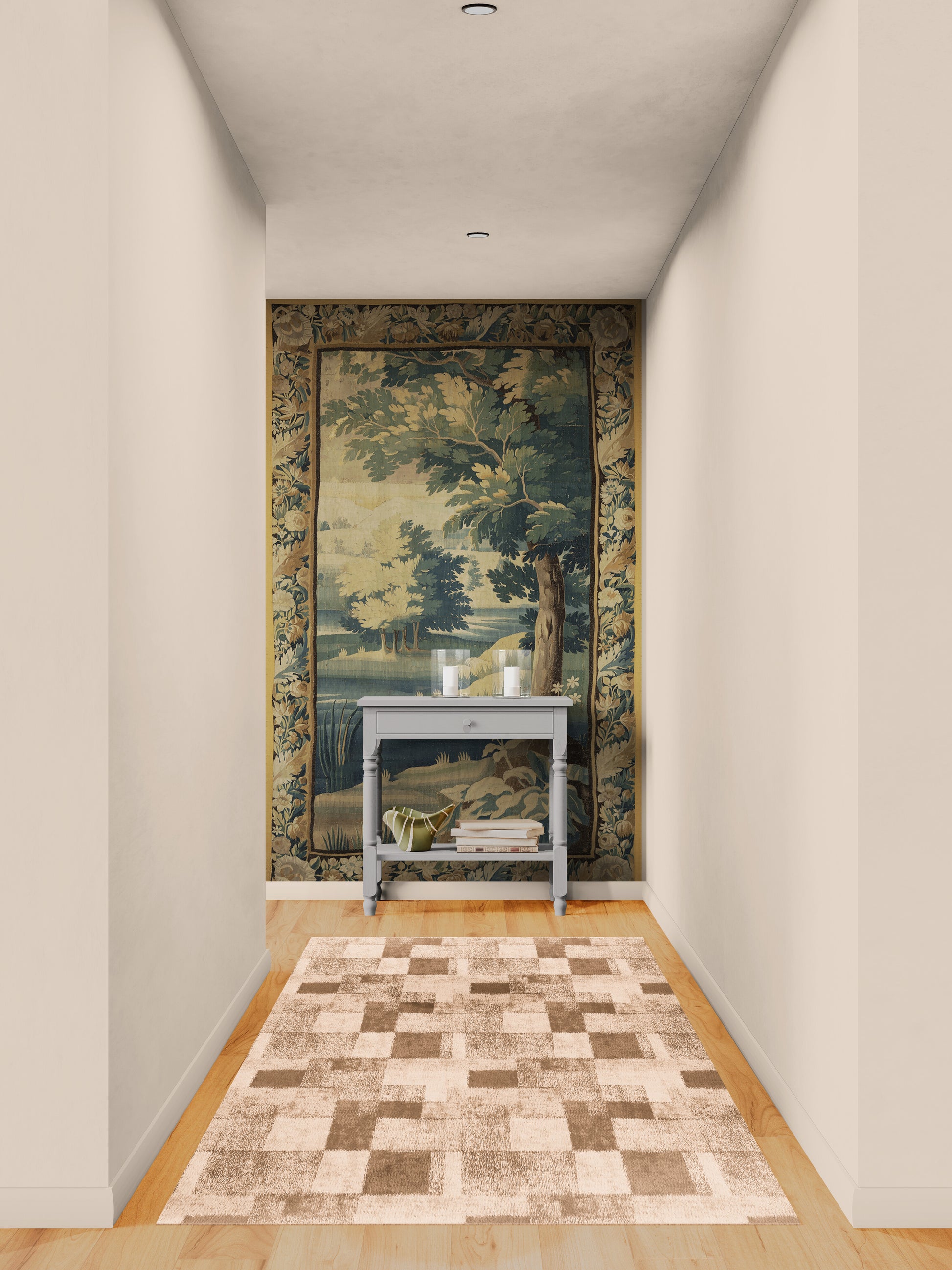 A long hallway with light beige walls and wood flooring, featuring a large vintage-style landscape tapestry on the back wall above a small gray console table. A patterned area rug in beige and brown tones is laid out on the floor in front of the tapestry.