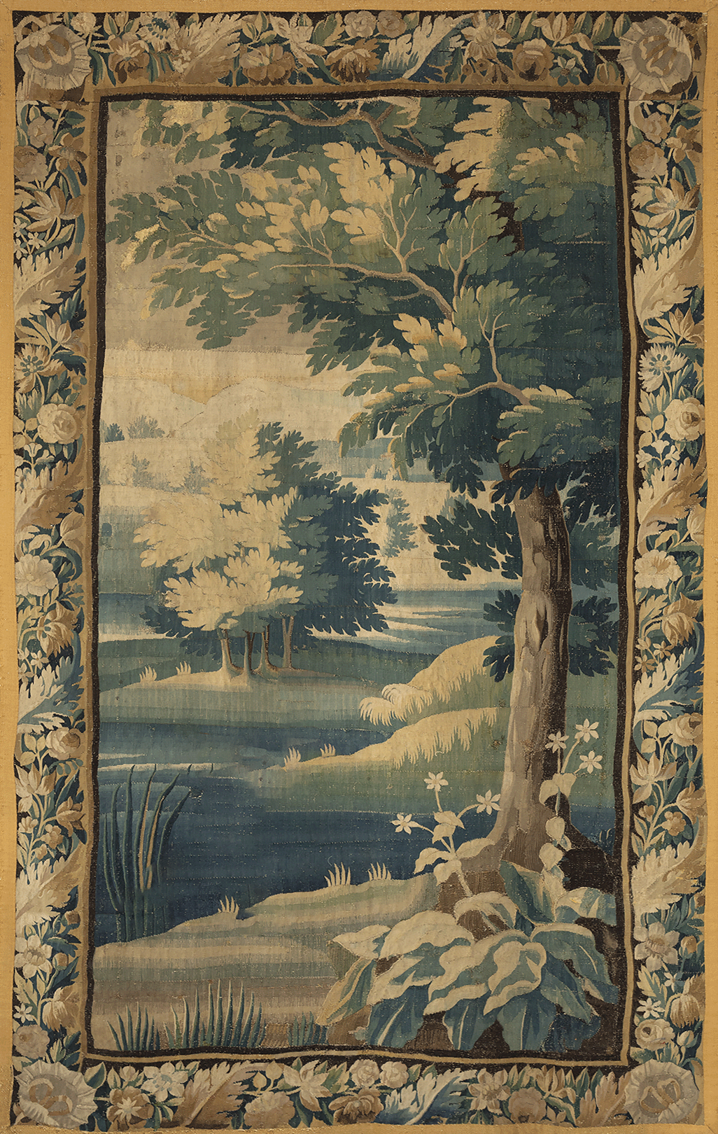 An antique tapestry featuring a scenic landscape with trees, a river, and a decorative floral border.