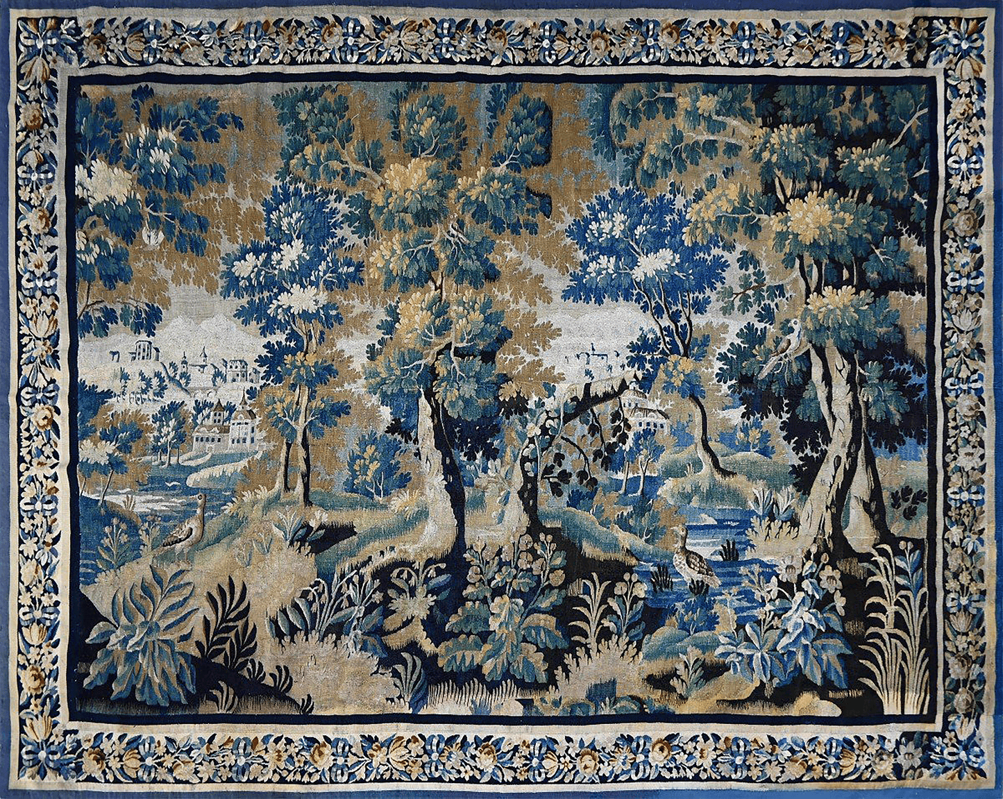 A square tapestry featuring a detailed landscape scene with blue and green trees, foliage, and a river, framed by an ornate floral border in blue, beige, and gold.