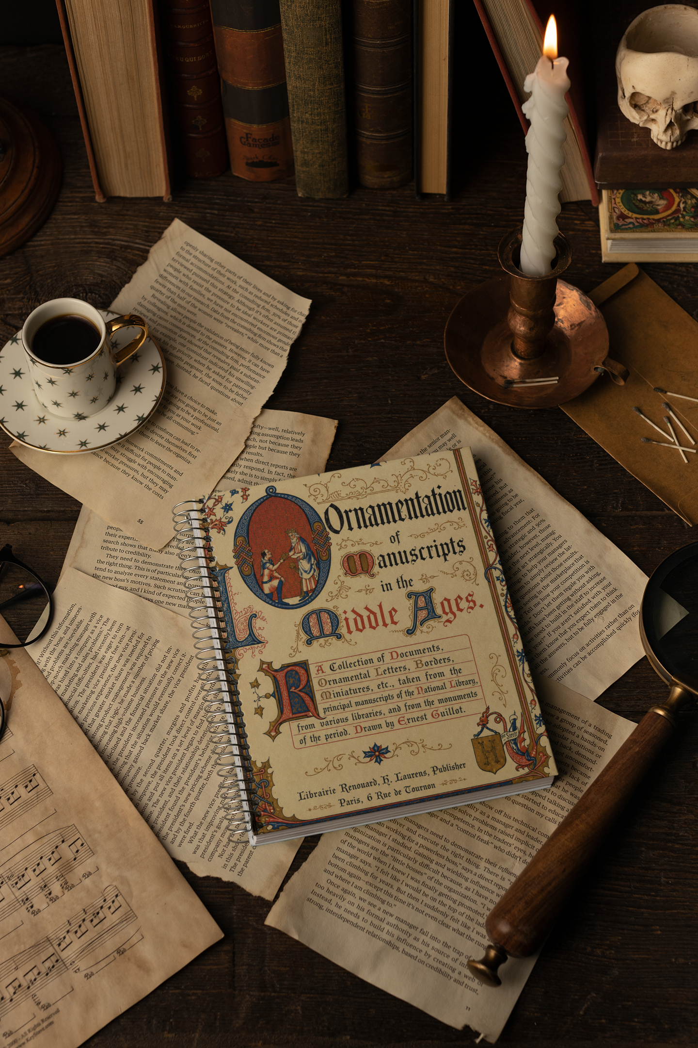 A vintage-style spiral notebook titled 'Ornamentation of Manuscripts in the Middle Ages' lies on scattered aged papers on a dark wooden table, surrounded by old books, a lit candle in a brass holder, a cup of coffee, and other moody props.