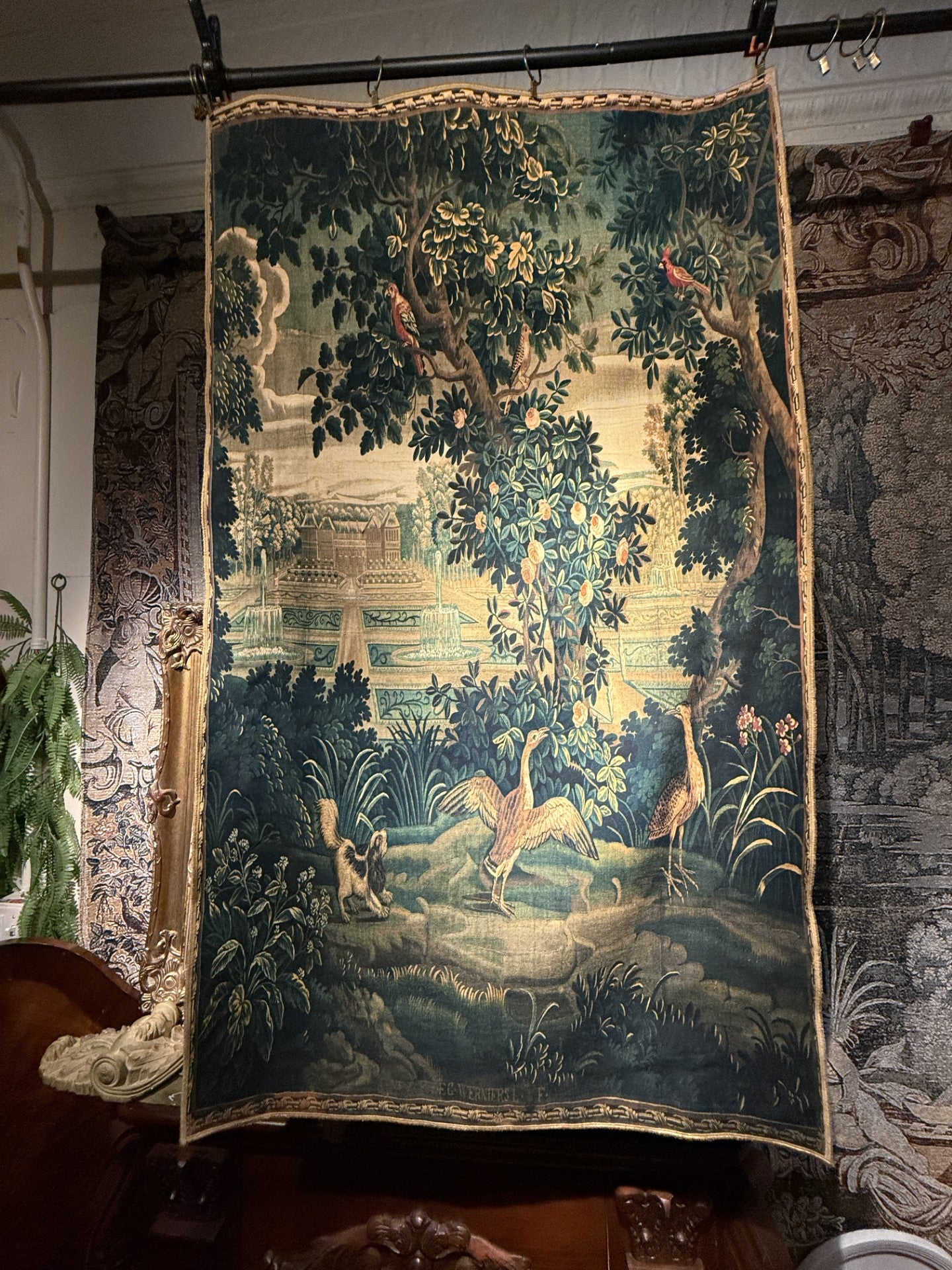 Vintage tapestry with nature scene and animals hanging on a wall.